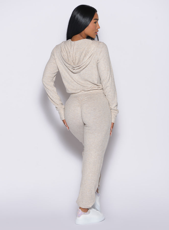 back profile view of a model wearing the Flirty Jumpsuit in Cozy oat color