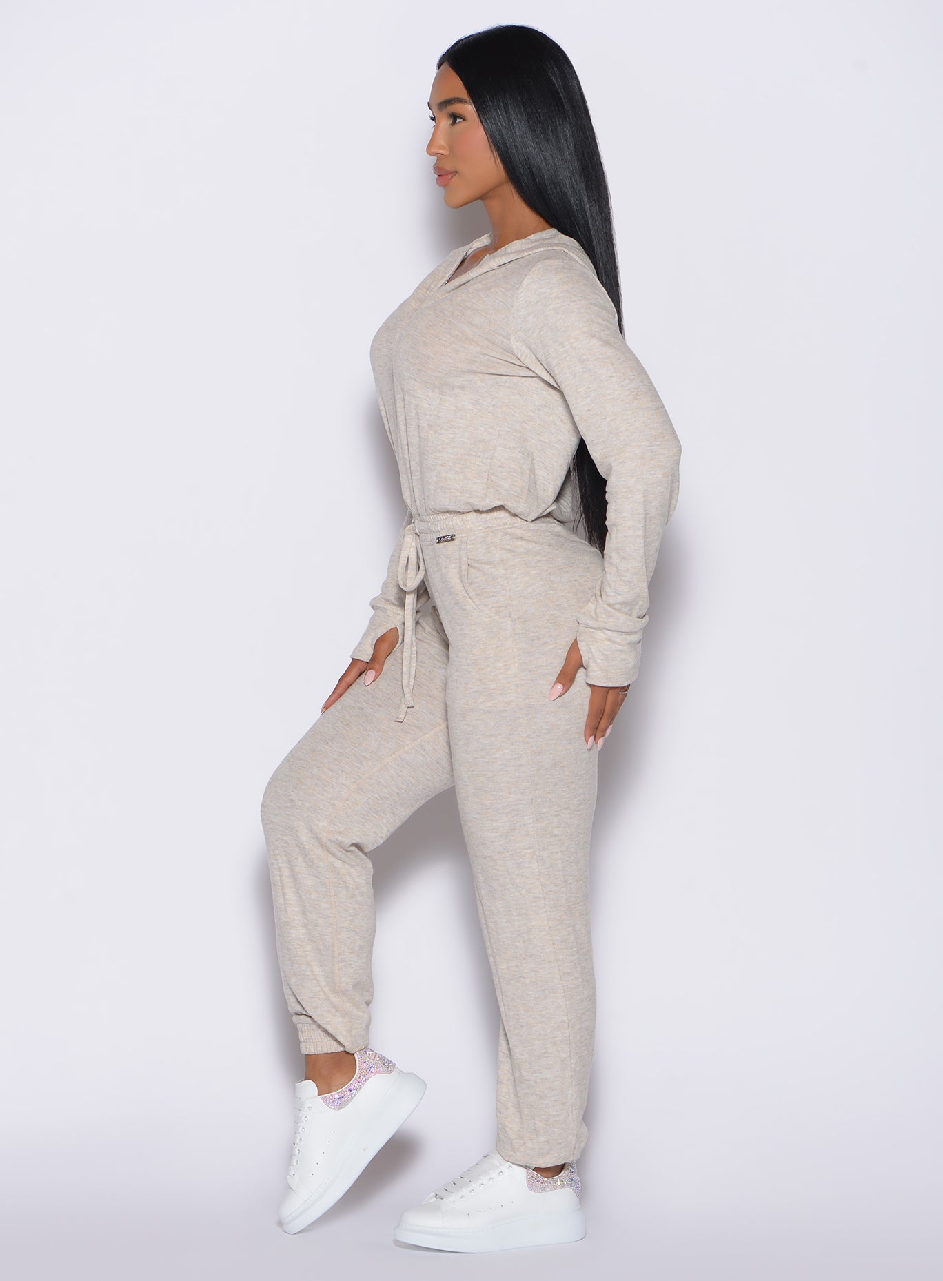 left side profile view of a model wearing the Flirty Jumpsuit in Cozy oat color