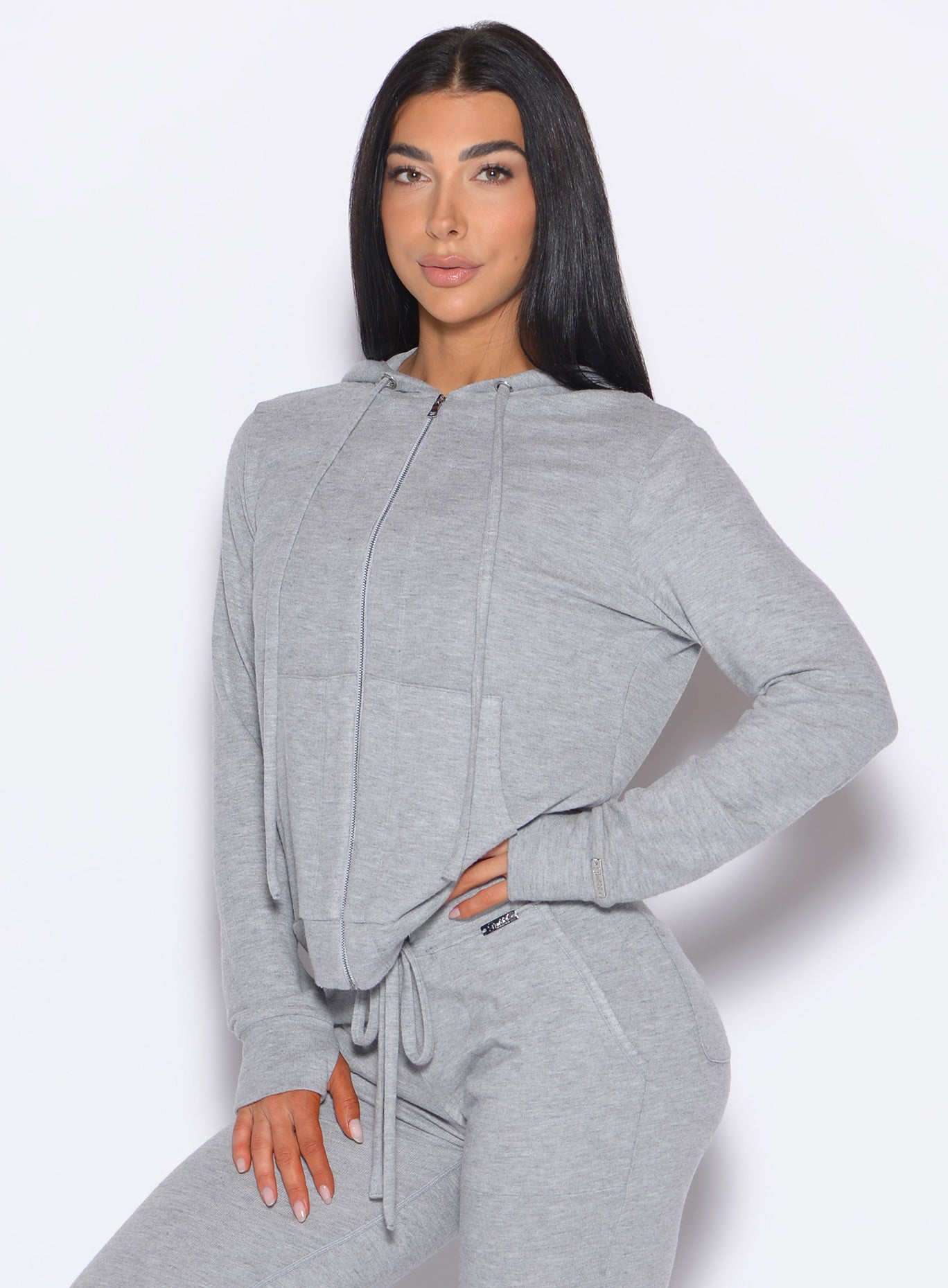 front left side profile view of a model with one hand on her waist wearing the Gym Crush Hoodie in Cozy Silver color