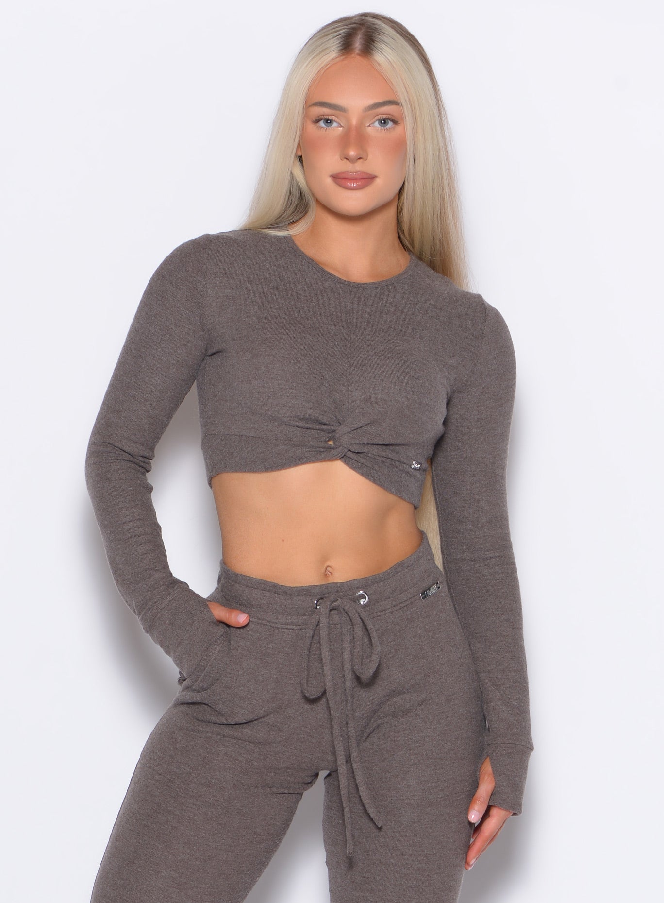 front profile view of a model with one hand inside the pocket of the joggers wearing the Love Knot Pullover in Cozy chocolate color