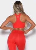 back profile of model wearing the Cross Over Halter Bra and the matching leggings in Cherry Bomb color