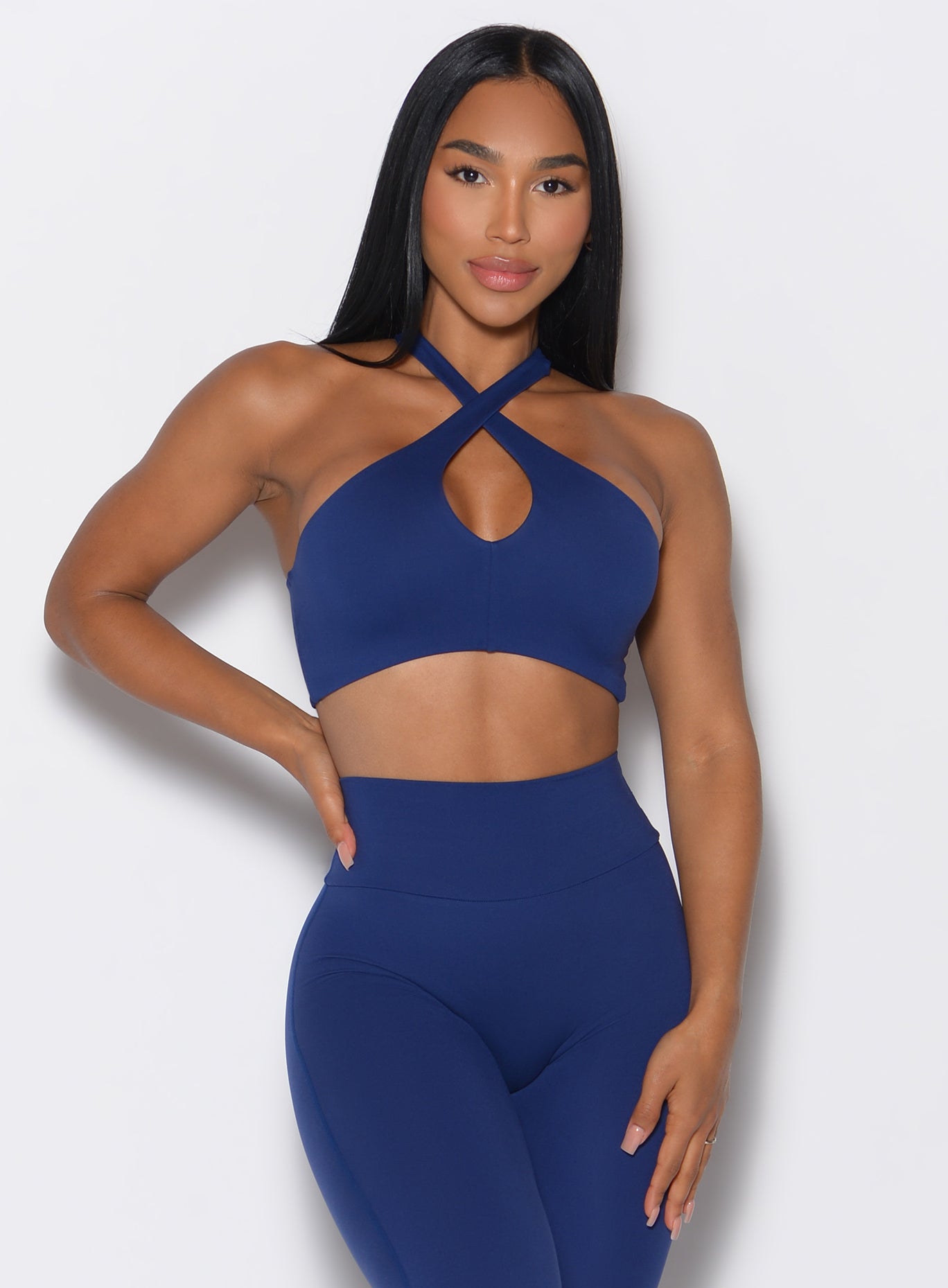 front profile picture of a model in our Cross Over Halter Bra and the matching leggings in Royal Indigo color