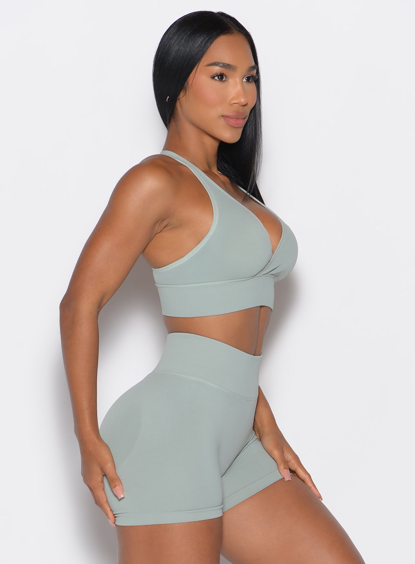 right side profile picture of a model facing forward wearing our cross over bra in light taupe color along with the matching shorts