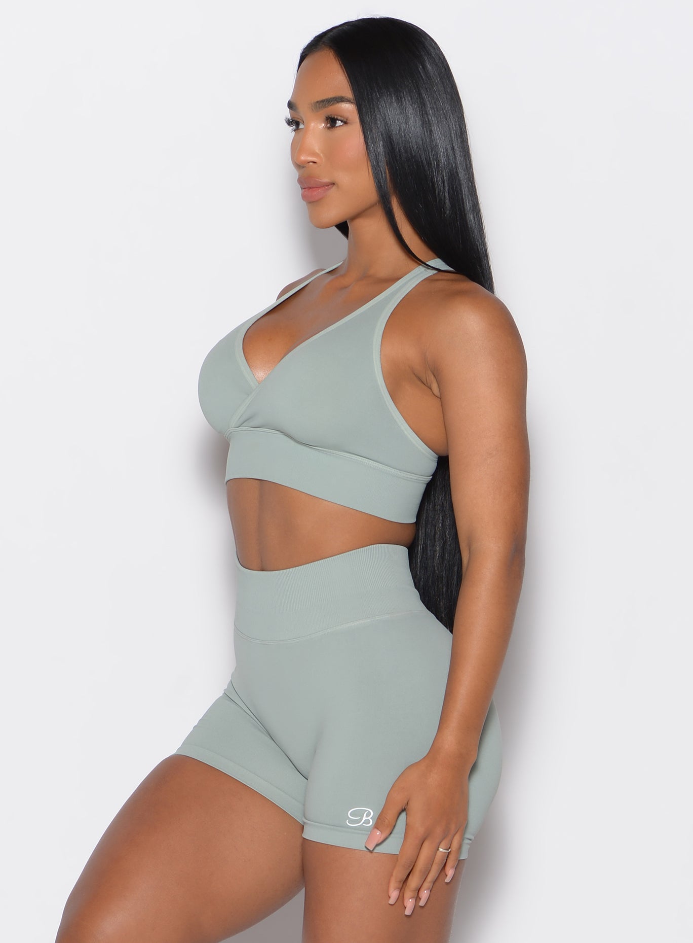 left side profile view of a model facing forward  wearing our cross over bra in light taupe color along with the matching shorts