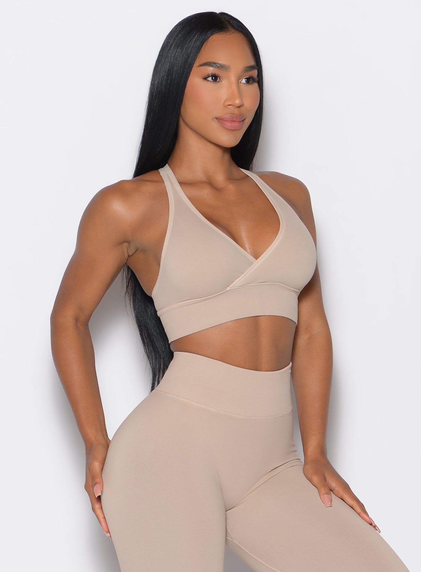 front  profile view of a model wearing our cross over bra in timeless taupe color along with the matching seamless leggings