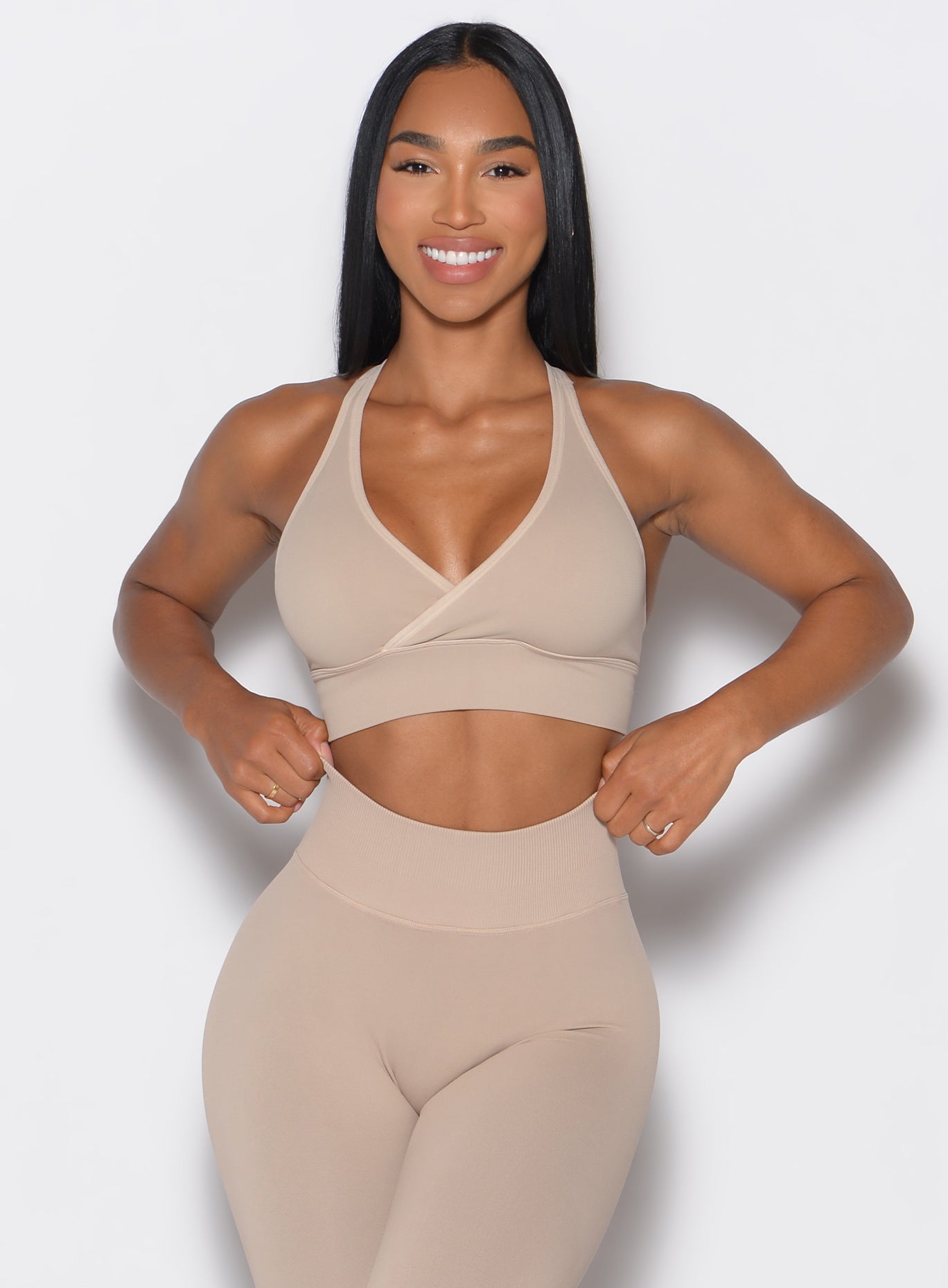 front profile view of a model wearing our cross over bra in timeless taupe color along with the matching leggings