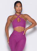 Model facing forward wearing our Cross Over Halter Bra and the matching leggings in Bright Plum color
