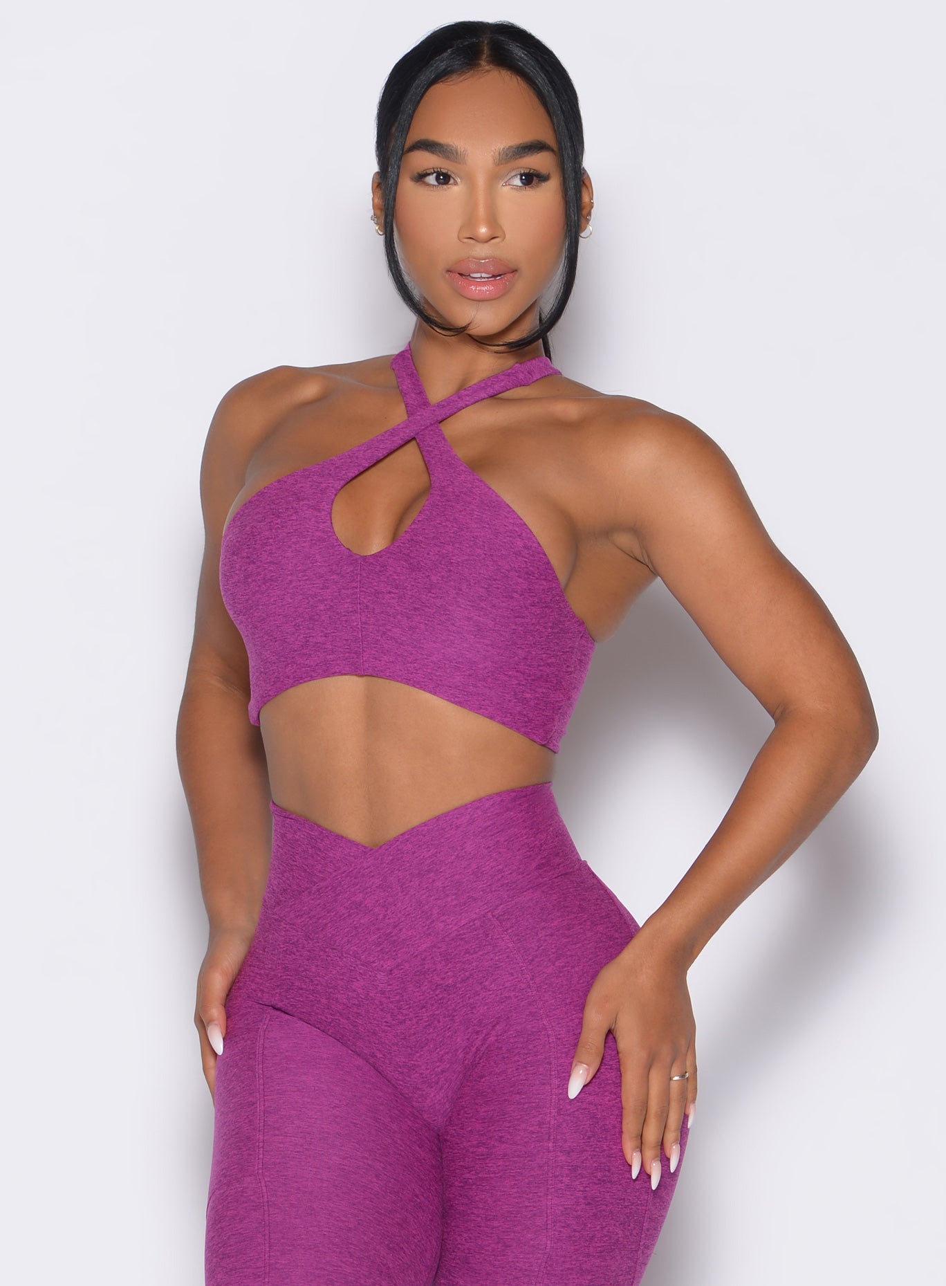 front profile view of a model wearing our Cross Over Halter Bra and the matching leggings in Bright Plum color
