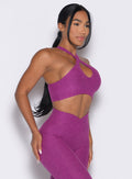 right side profile view of a model facing forward wearing our Cross Over Halter Bra and the matching leggings in Bright Plum color