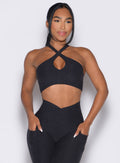 front profile view of a model wearing our Cross Over Halter Bra and the matching leggings in Heathered Black color