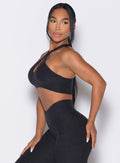 left side view of a model wearing our Cross Over Halter Bra and the matching leggings in Heathered Black color
