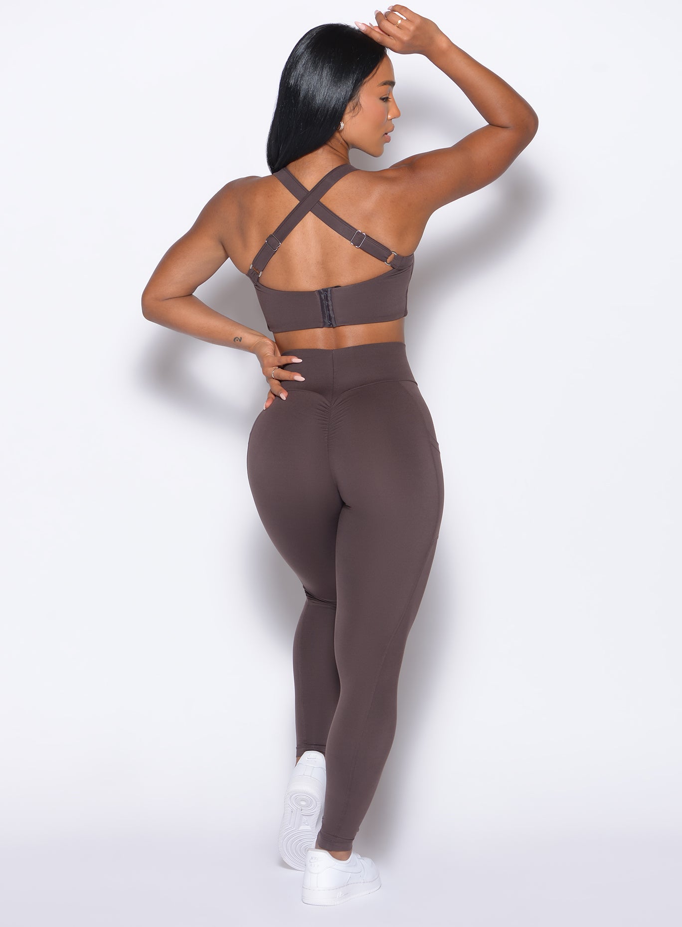 back profile view of our model with one hand on her waist wearing the Curves 2.0 Leggings in Seal Brown color 