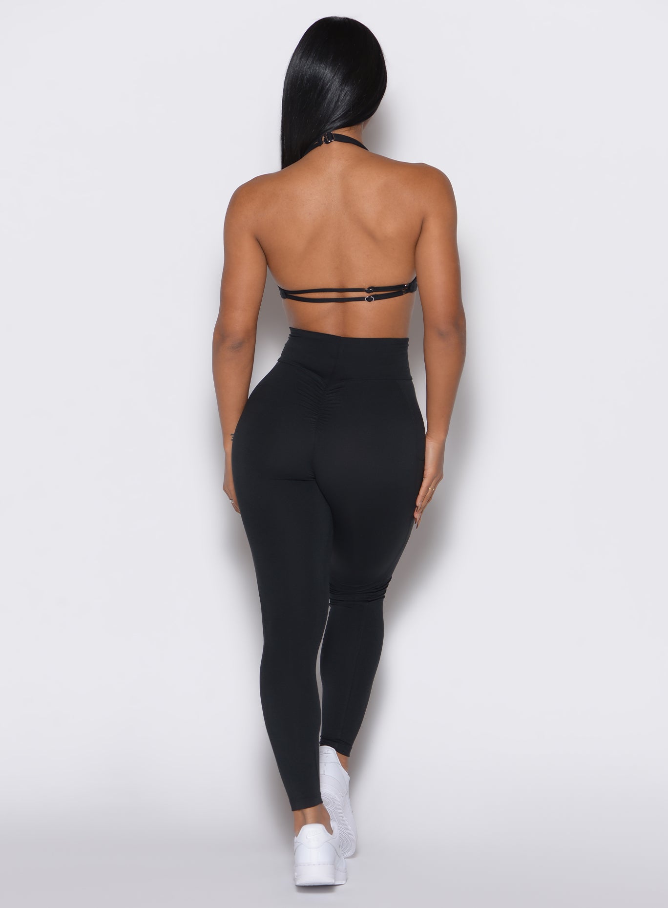 back profile view of a model wearing our black curves leggings along with a matching sports bra 
