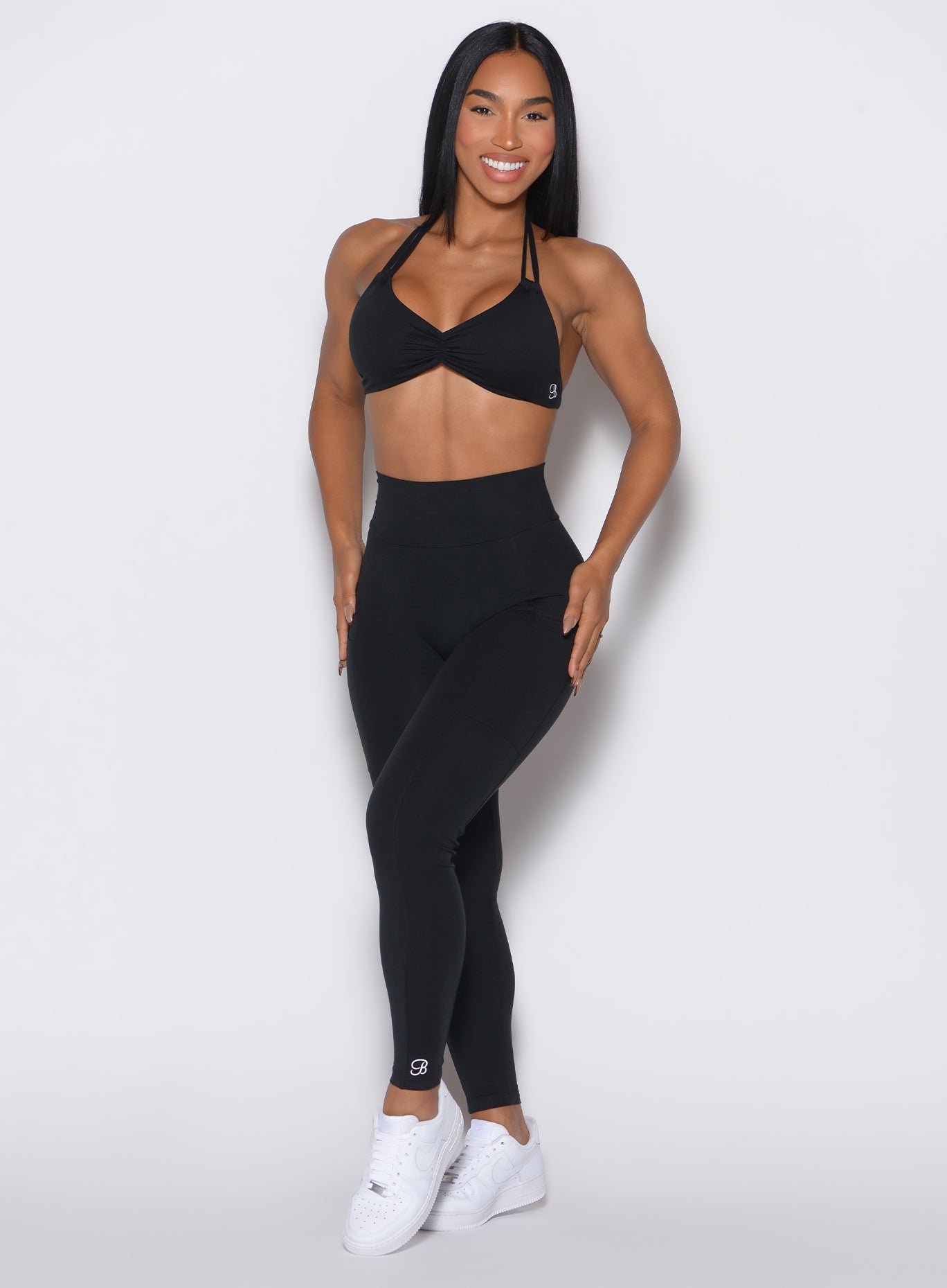 A front profile picture presents a model facing forward, showcasing our black Curves leggings paired with the matching sports bra