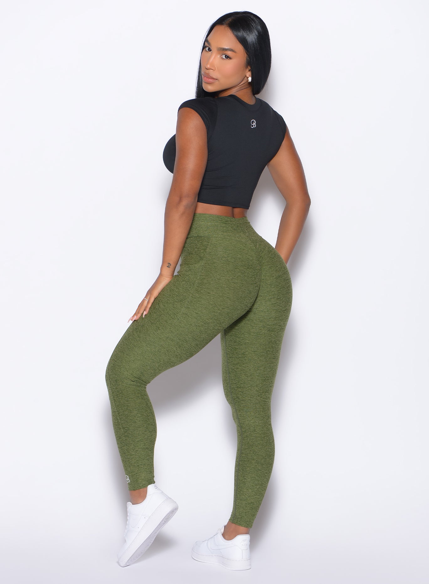 Left side profile view of our model looking over her shoulder wearing the Curves 2.0 Leggings  in Juniper color paired with the Flex Crop Tee in Black