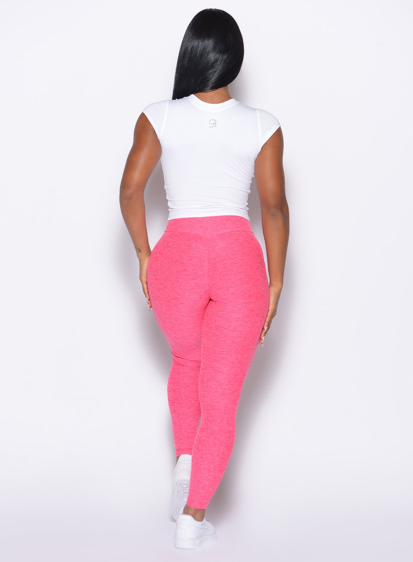 back profile of a model wearing the Flex Long Tee in White color and the Curves 2.0 Leggings in Neon Flame color
