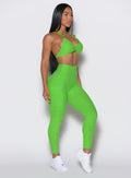 right side profile view of a model wearing our curves leggings in Neon Lime Green color along with the matching sports bra