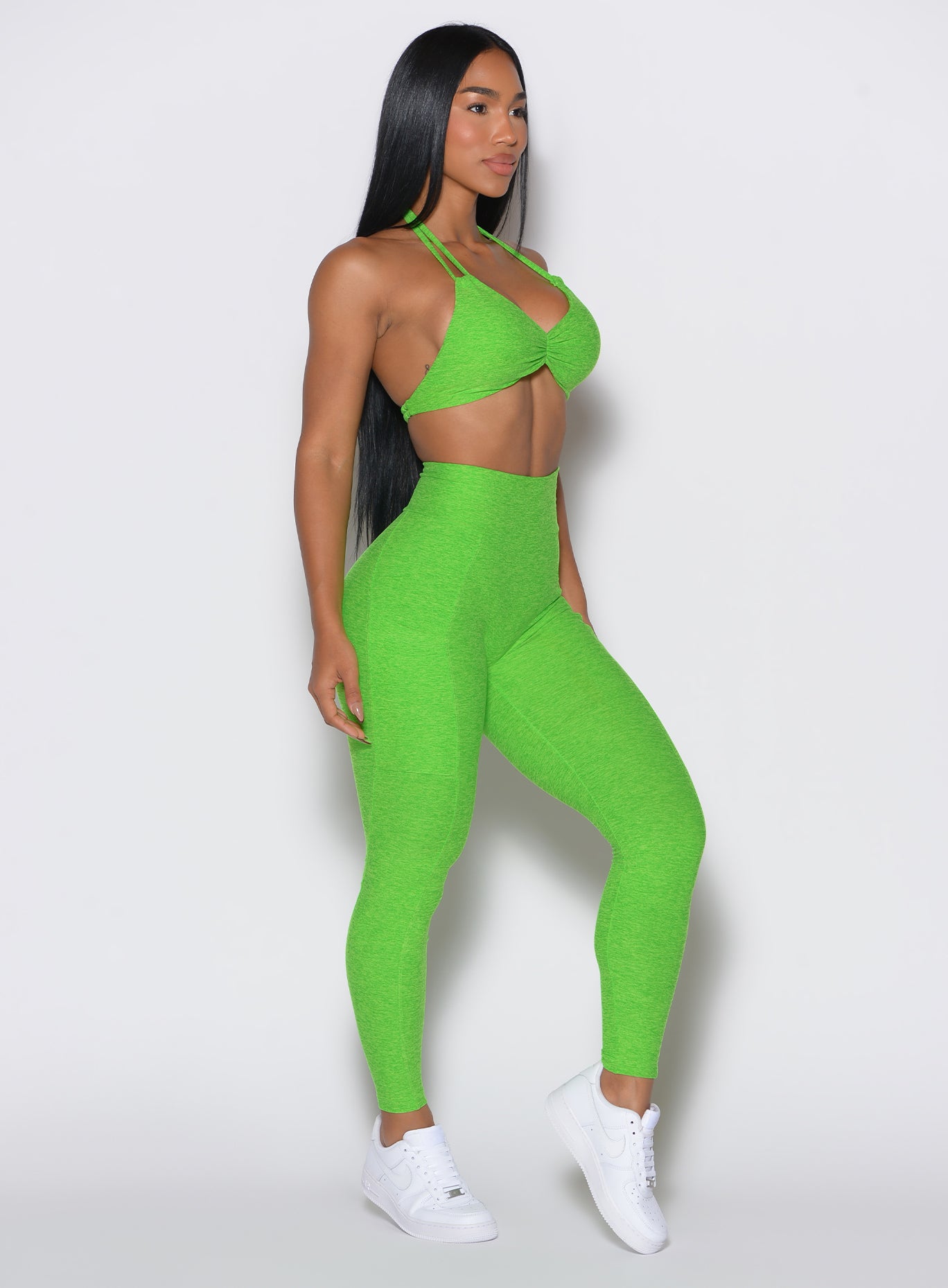 right side profile view of a model wearing our curves leggings in Neon Lime Green color along with the matching sports bra