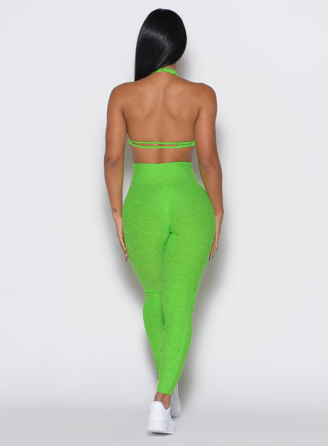back profile view of a model wearing our curves leggings in Neon Lime Green color along with the matching sports bra