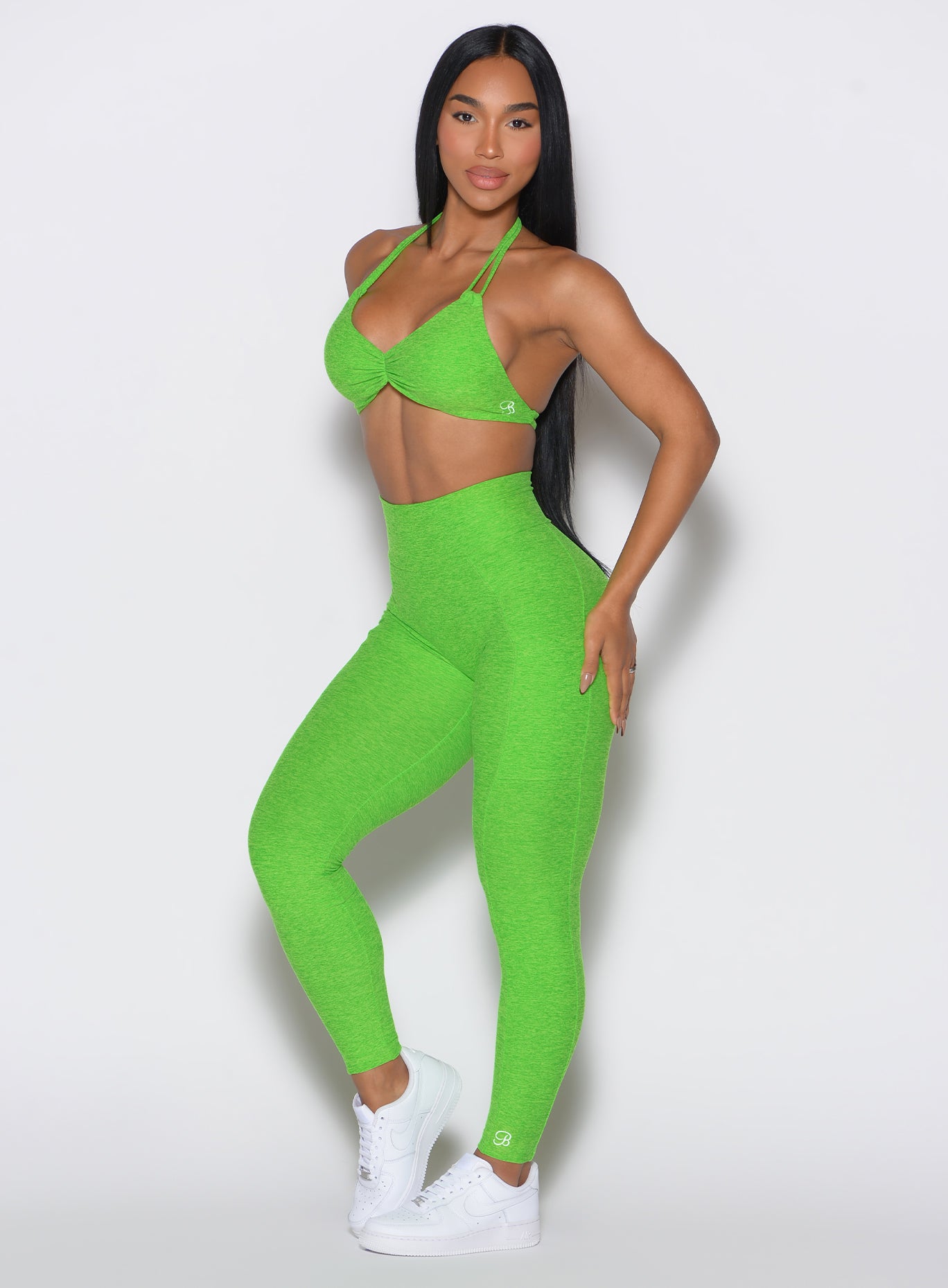 left side profile view of a model angled slightly to her left  wearing our curves leggings in Neon Lime Green color along with the matching sports bra