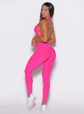 left side  profile view of a model facing to her left wearing our curves leggings in Neon Pink Berry color along with the matching bra