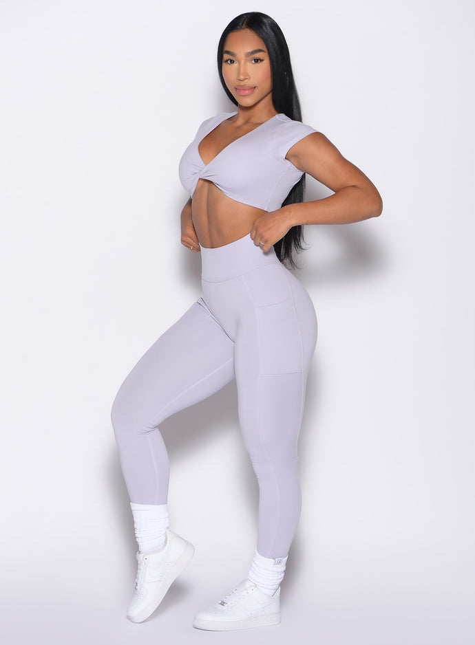 front left side profile view of a model adjusting the waistband wearing the Define Leggings in Galactic Lilac color