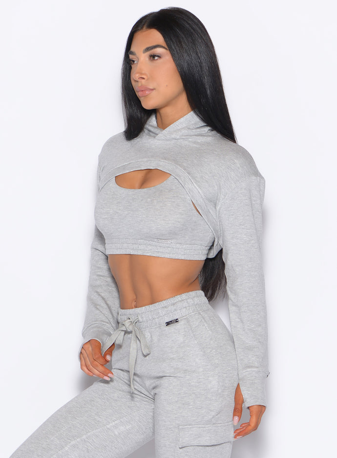 Left side profile view of a model angled slightly to her left wearing our Sweat Bolero Hoodie and the matching Joggers in Light Heather Grey color