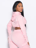 Right side view of a model facing to her right wearing our Sweat Bolero Hoodie and the matching Joggers in Tickled Pink color