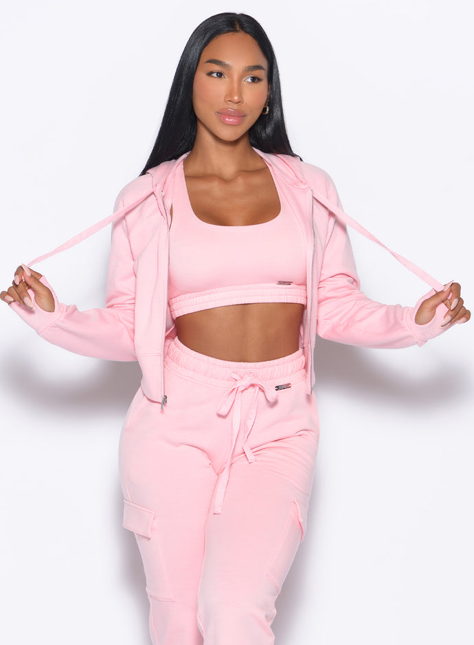 front profile view of our model holding both the hoodie strings wearing the Sweat Hoodie in tickled pink color