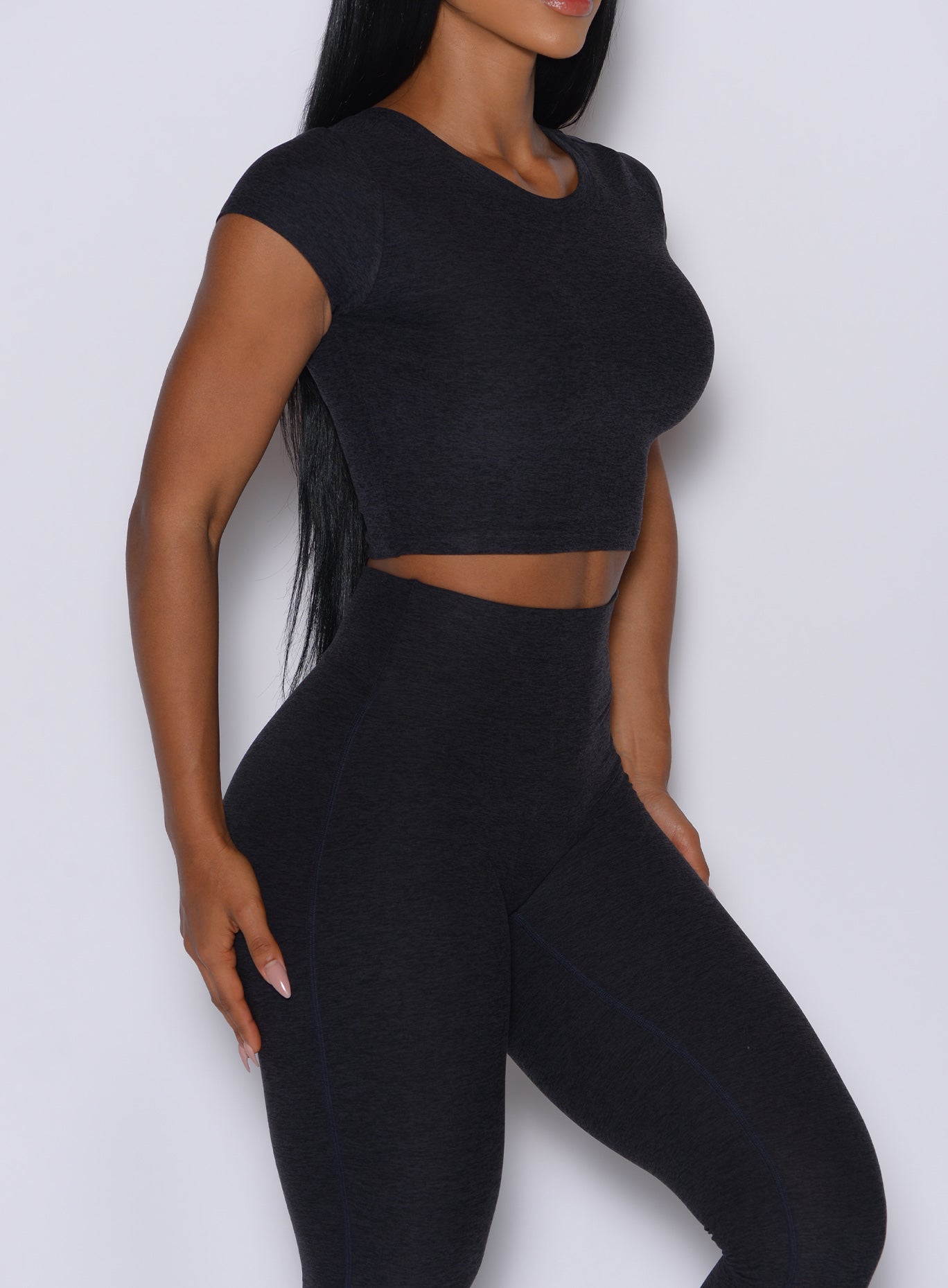 Right side close up view of a model facing to her right wearing our Fit Fam Active Tee in Onyx color along with the matching Leggings