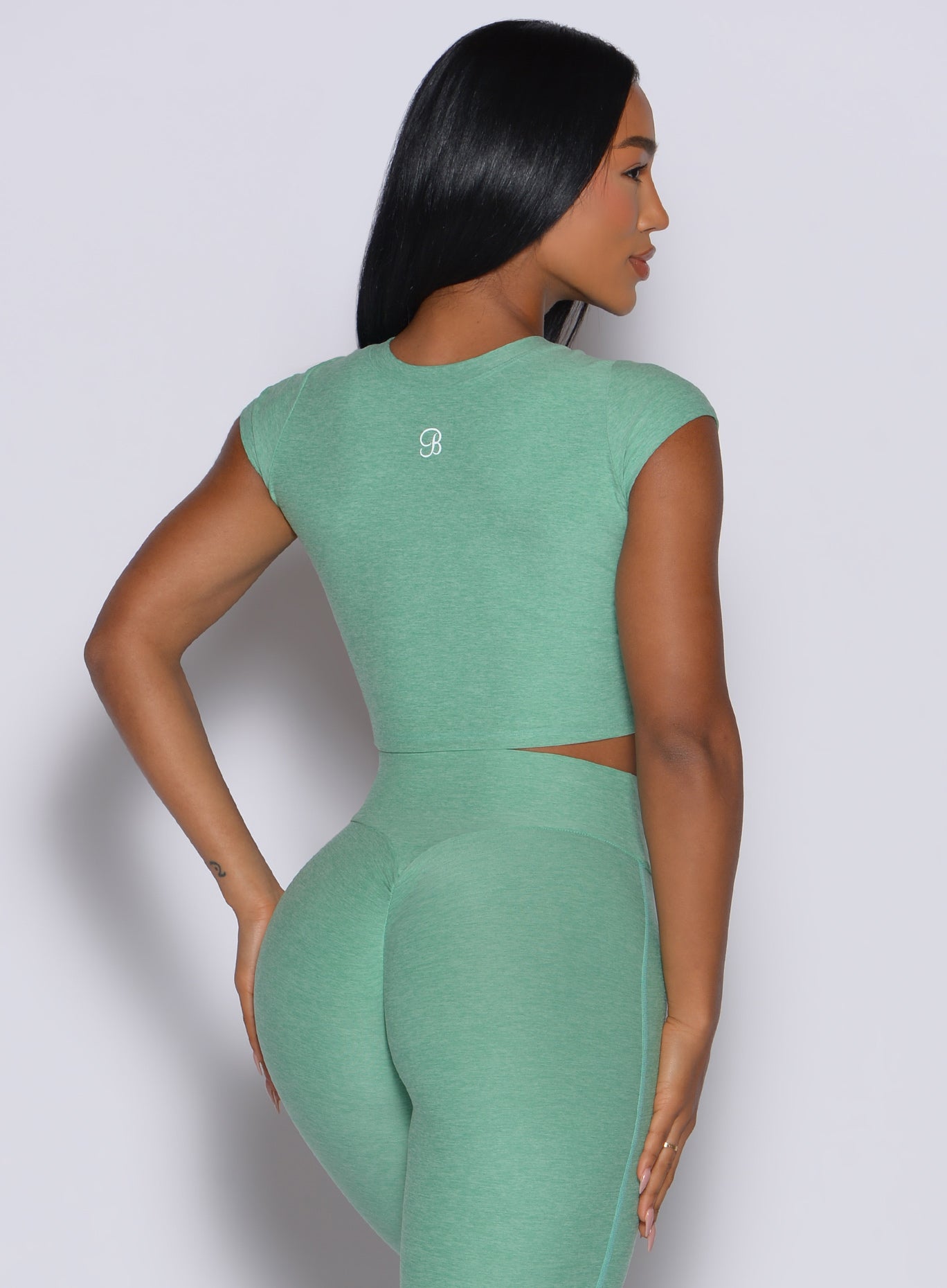 back profile view of a model wearing our fit fam active tee in sage color along with the matching leggings