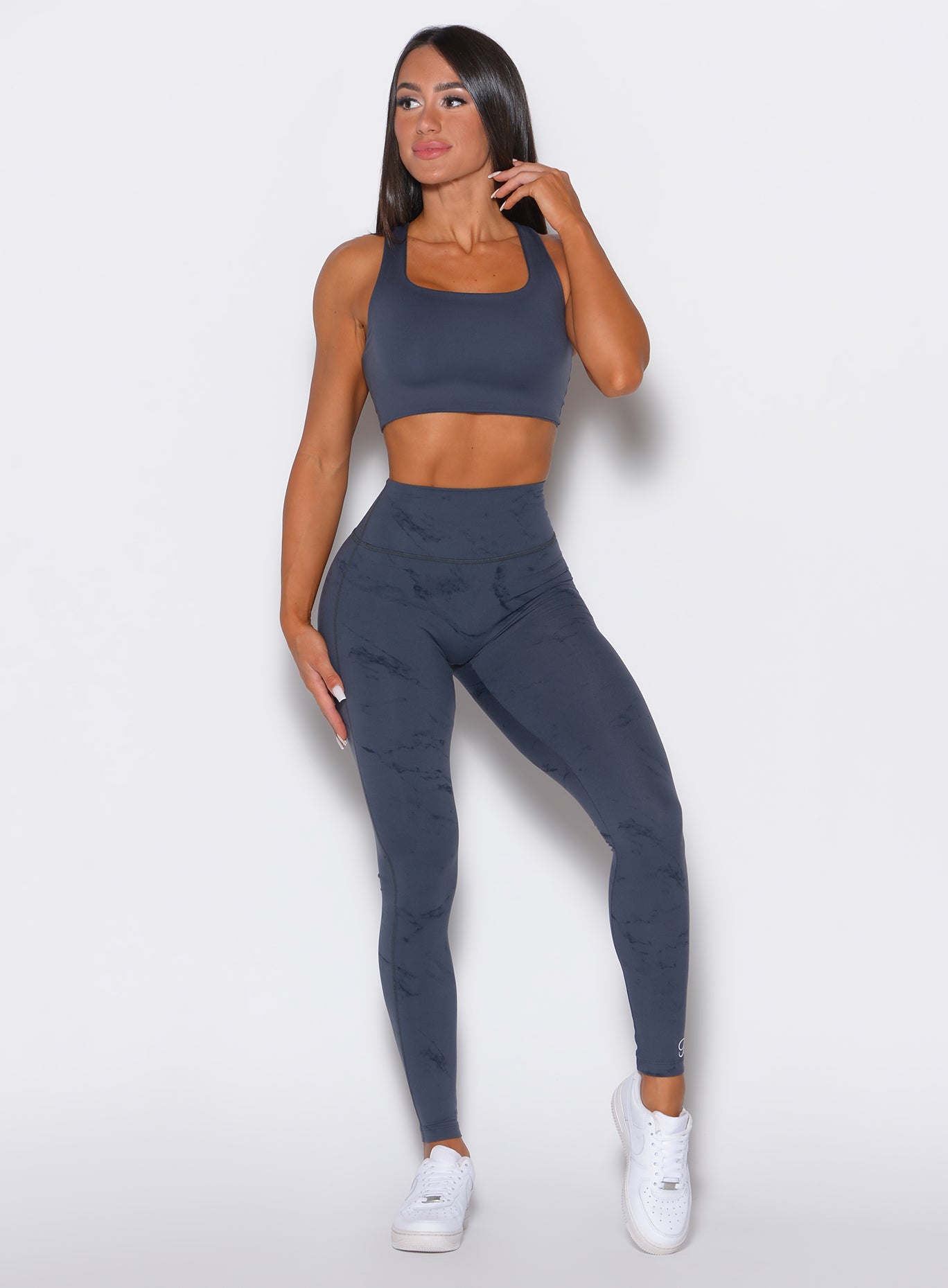 Front  profile view of a model wearing our fit marble leggings in thunder gray color along with a matching bra