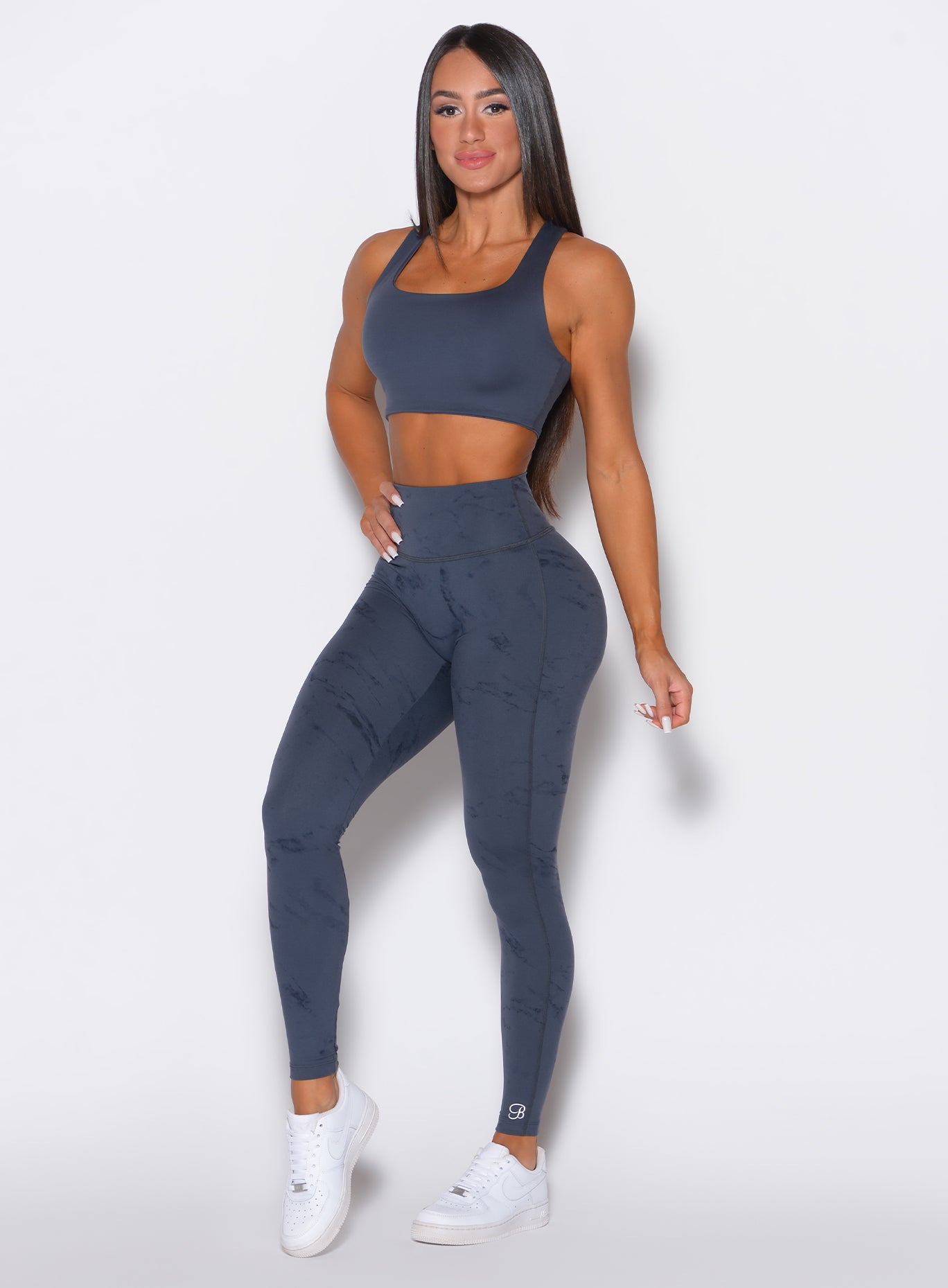 front profile view of a model wearing our fit marble leggings in thunder gray color along with a matching sports bra