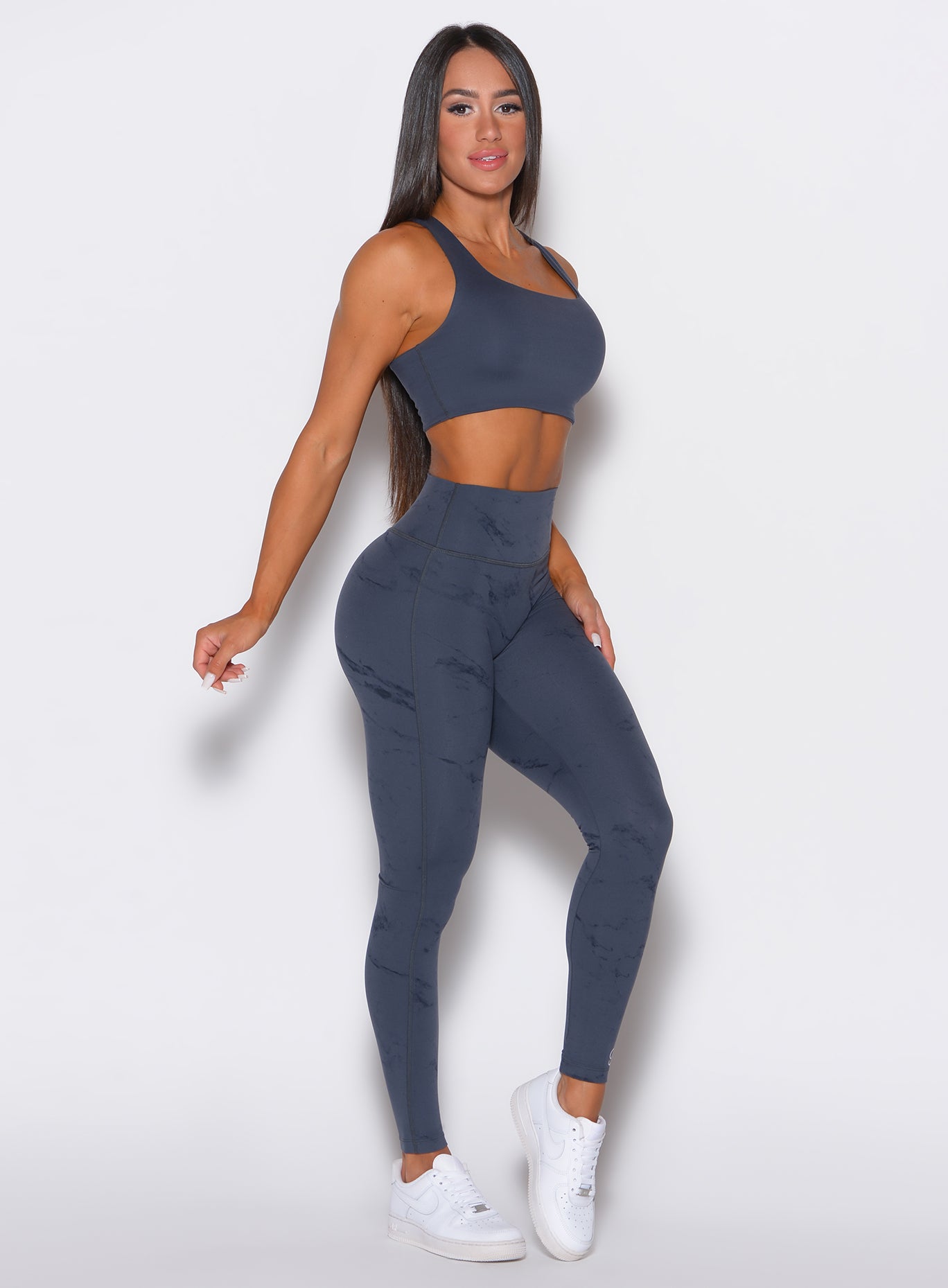 right side profile view of a model wearing our fit marble leggings in thunder gray color along with a matching bra