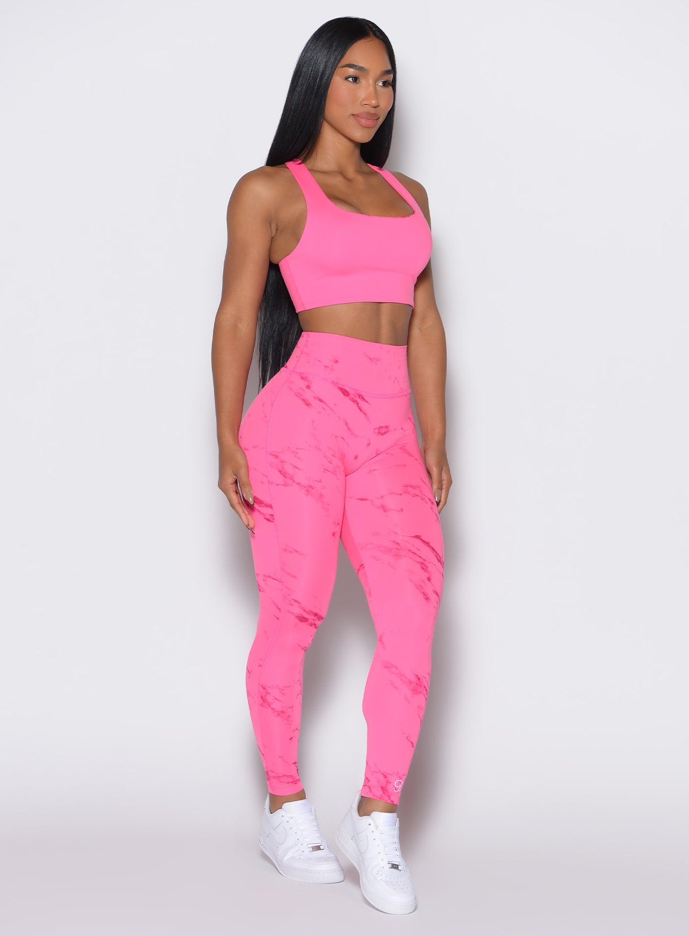 front profile view of a model angled slightly to her left wearing our fit marble leggings in Cotton Candy Skies color along with a matching bra