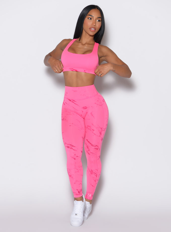 front profile picture of a model wearing our fit marble leggings in Cotton Candy Skies color along with a matching bra