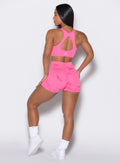 back profile view of a model wearing our fit marble shorts in Cotton Candy Skies color along with a matching sports bra