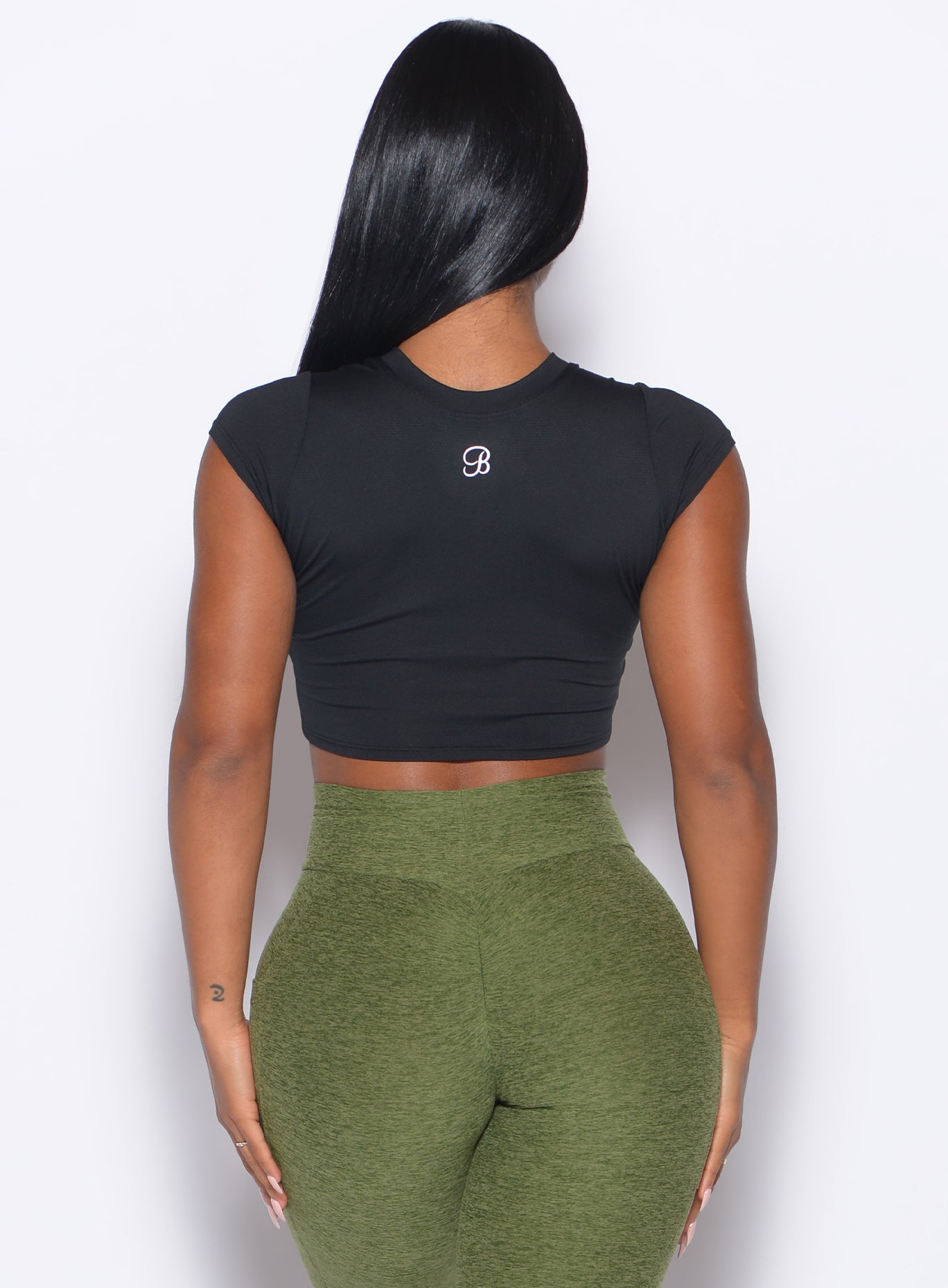 back profile of a model wearing the Flex Crop Tee in Black color and the Curves 2.0 Leggings in Juniper color
