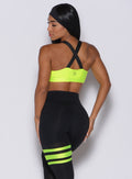 Back profile view of a model in our glow sports bra in neon yellow and a matching leggings