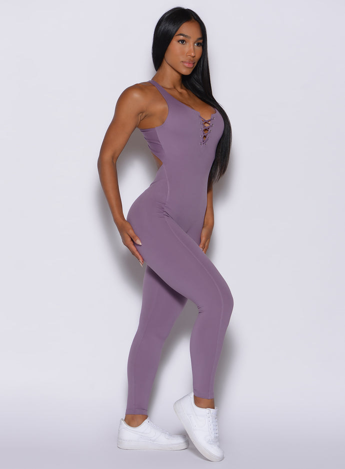 Right side profile view of a model wearing our laced bodysuit in Violet Frost color