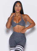 front profile view of our model holding the bra strap with one hand and the waistband of the leggings with the other hand wearing the Dragonfly Bra in Shadow color