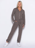 front profile view of a model with one hand inside the pocket wearing the Flirty Jumpsuit in Cozy chocolate color