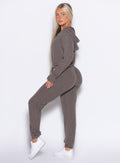 left side profile view of a model looking over her shoulder wearing the Flirty Jumpsuit in Cozy chocolate color