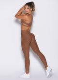 left side profile view of a model looking over her shoulder wearing the V Butt Lift Leggings in Coffee Bean color