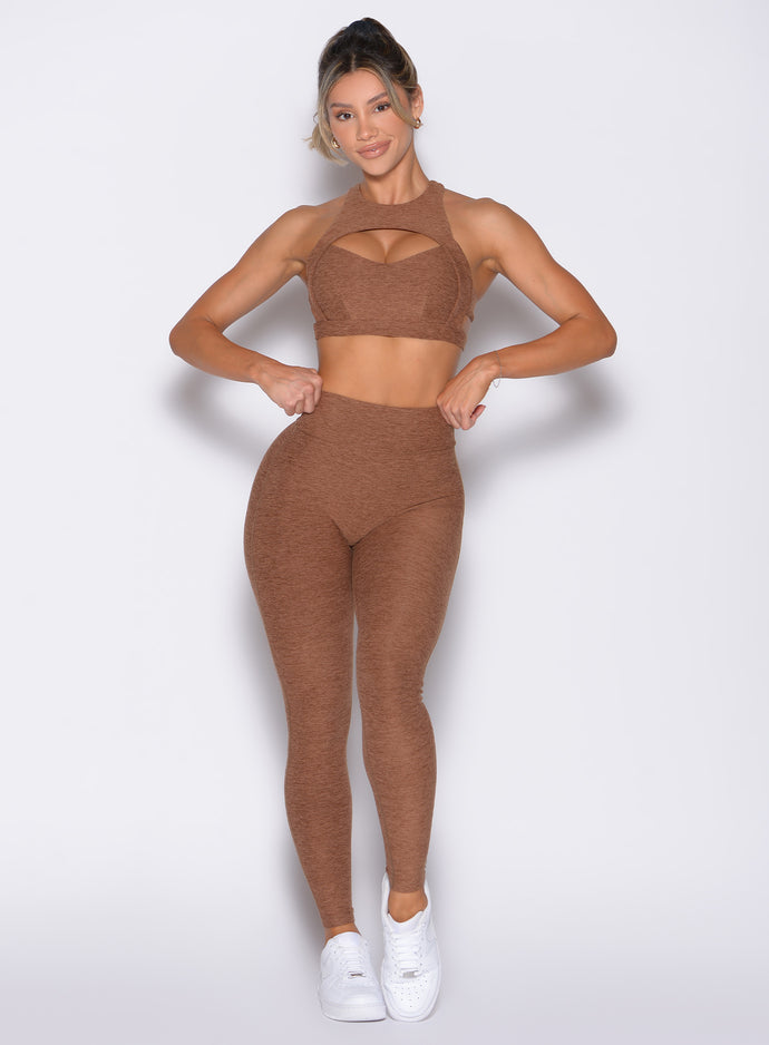 front profile view of a model with both hands on the waistband wearing the V Butt Lift Leggings in Coffee Bean color