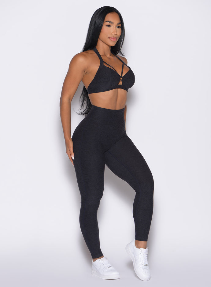 front right side profile view of a model wearing the Movement Leggings in Heathered Black color paired with the matching bra