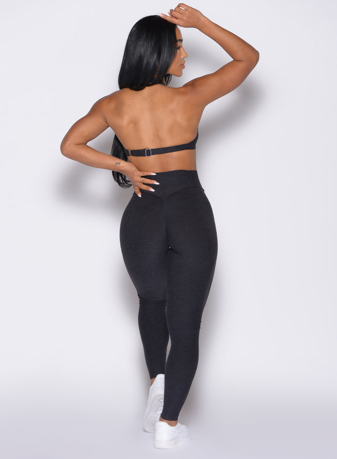 back profile view of a model with one hand on her waist wearing the Movement Leggings in Heathered Black color