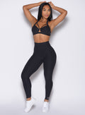 front profile view of a model with both hands placed behind her head wearing the Movement Leggings in Heathered Black color