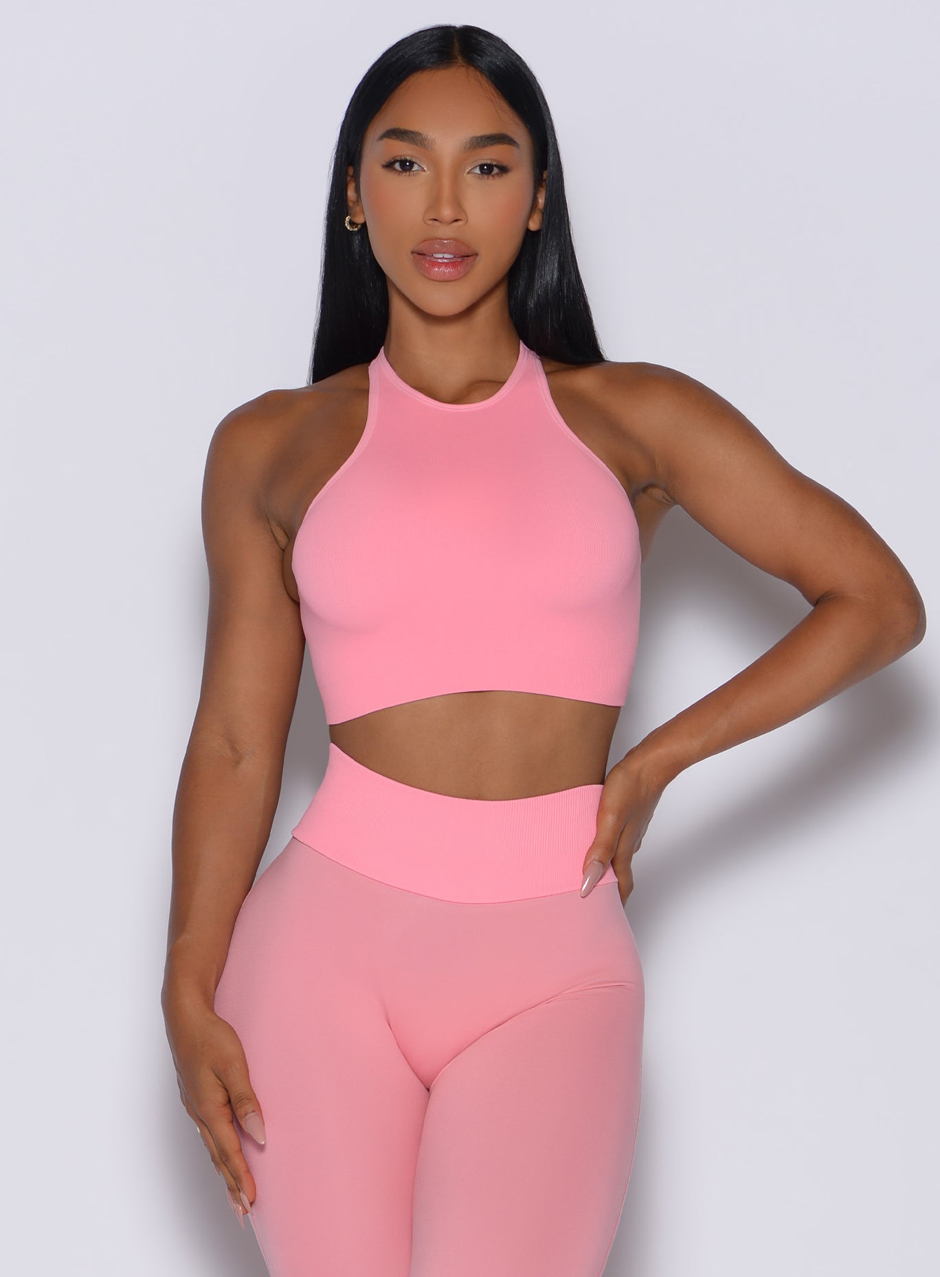 Model facing forward wearing our Lifter Seamless Bra and the matching leggings in Peach Burst color