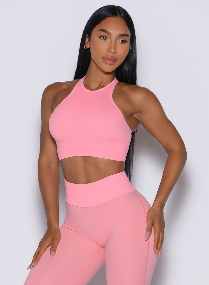 front profile view of a model wearing our Lifter Seamless Bra and the matching leggings in Peach Burst color